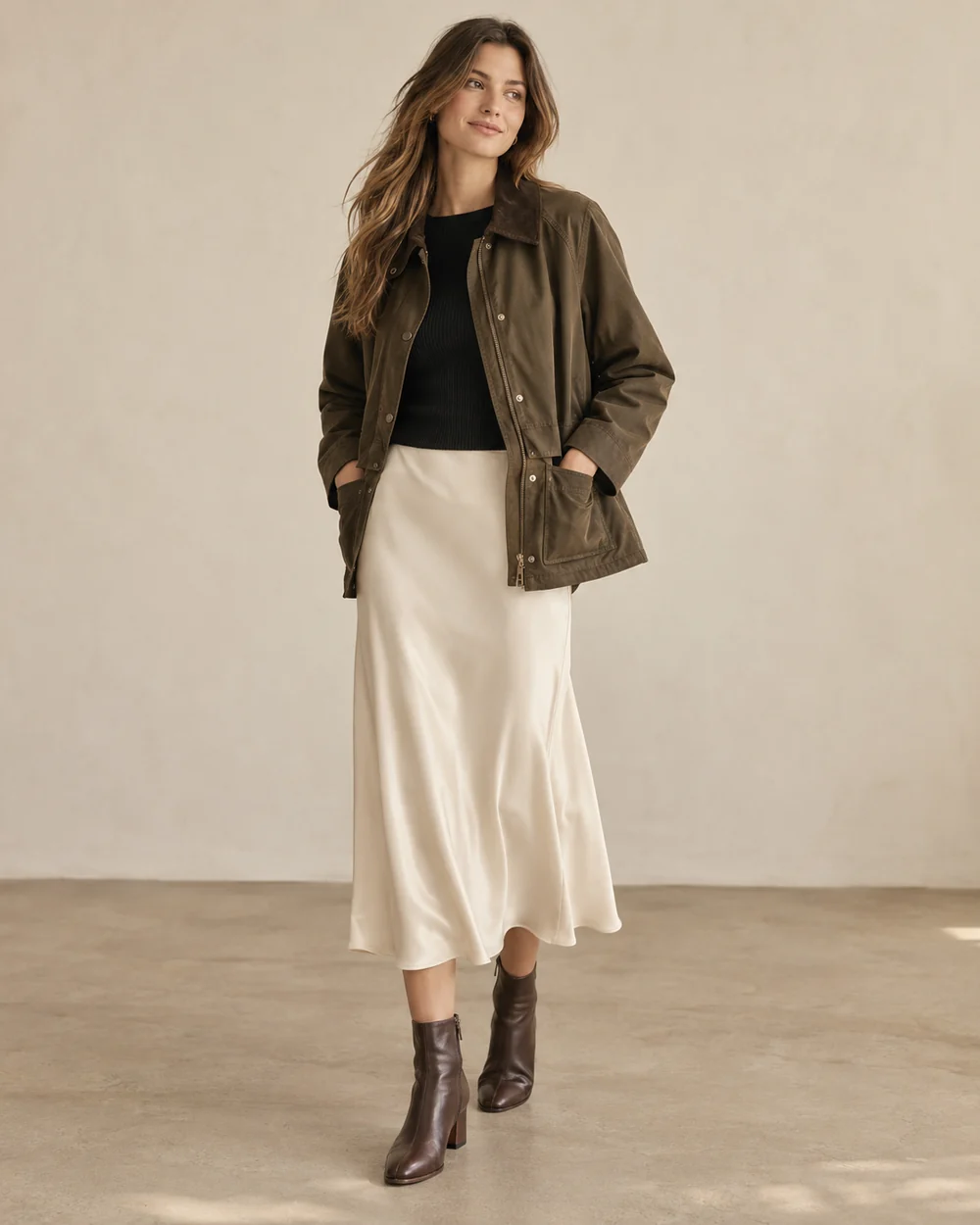 Olive barn jacket over a black knit and ivory satin midi skirt